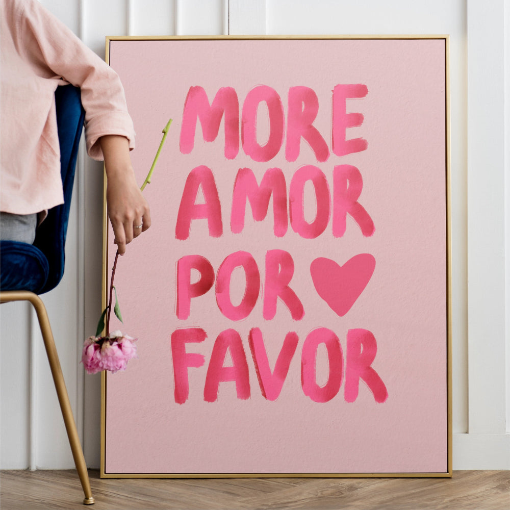 Pink poster with 'More Amor Por Favor' text on a white wall.